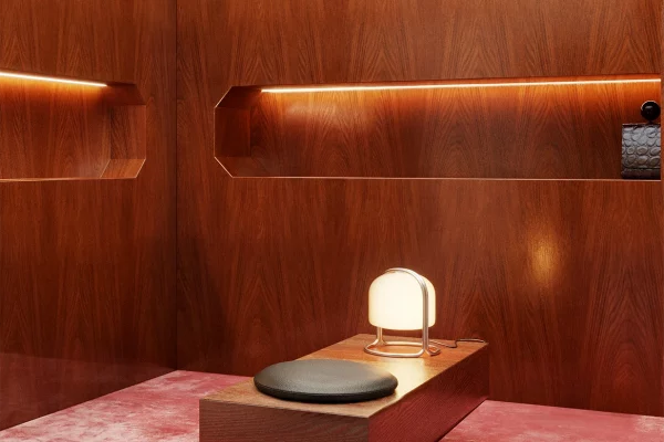 NOVU concept store by NOCOD Studio — private listening booth. Warm oak panels, LED recessed niche, custom bench with black leather cushion, deep rose velvet carpet