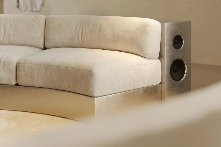 NOVU concept store — curved sofa section with integrated brushed steel speaker panel. Ivory velvet, metal base. Custom furniture design by NOCOD Studio.