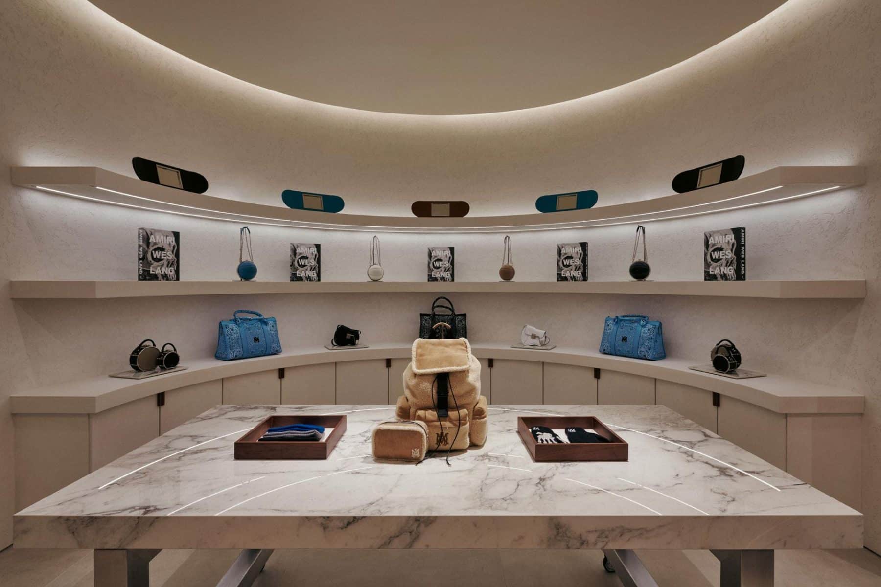 AMIRI Chicago customization atelier by NOCOD Studio, curved intimate room with central marble worktable and integrated display.